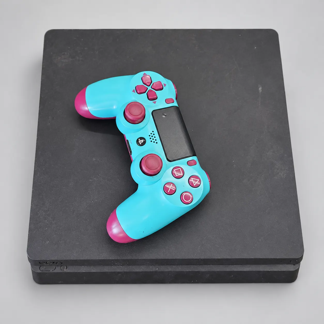 Used Sony PS4 Slim 500GB with turquoise and magenta controller on an AI-enhanced gray background; see original gallery photos.